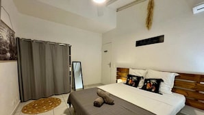 A bedroom with a bed, a mirror, a curtain, and a wall-mounted air conditioner.