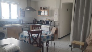 A compact kitchen with a dining area, a washing machine, and a small table with a chair. - Wheelchair-accessible house, 15min walk to beaches and 2min to town center. (Jard-sur-Mer)