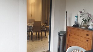 A room with a wooden floor, a dining table with chairs, a small cabinet, and a trash can. - Wheelchair-accessible house, 15min walk to beaches and 2min to town center. (Jard-sur-Mer)