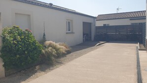 A narrow concrete pathway leading to a white building with a tiled roof. - Wheelchair-accessible house, 15min walk to beaches and 2min to town center. (Jard-sur-Mer)