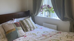 A bedroom with a bed, a window with curtains, and a hanging light fixture.