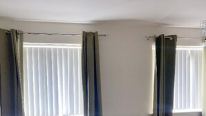 A bedroom with a bed, a radiator, and curtains on the windows.