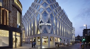 Um edifício moderno com fachada geométrica marcante e a inscrição "John Lewis" em destaque.