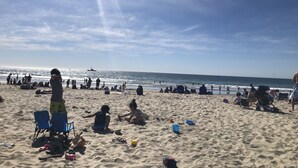 A beach with people sitting and walking, and a ship in the distance. - Beachee Townhouse  (San Diego)