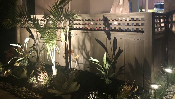 A well-lit outdoor area with a patio, potted plants, and a wooden fence. - Beachee Townhouse  (San Diego)
