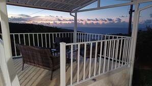 A covered outdoor area with a white railing, wicker furniture, and a view of the ocean. - Private Villa, Ocean & Mountain view with Solar Heated Pool. (Quebradillas)