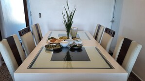 A dining table with multiple dishes and a plant centerpiece, surrounded by chairs. - Private Villa, Ocean & Mountain view with Solar Heated Pool. (Quebradillas)