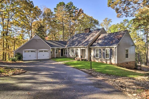 Une maison à deux étages avec un garage, un porche à l’avant et une allée menant au garage.