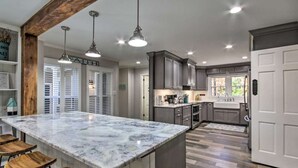 Una cocina con una isla de mármol, taburetes de madera, luces colgantes y armarios empotrados.