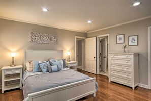 Une chambre à coucher comprenant un lit, des tables de chevet, une commode et une porte donnant sur une autre pièce.