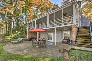 A two-story house with a covered patio, outdoor furniture, and a brick exterior.