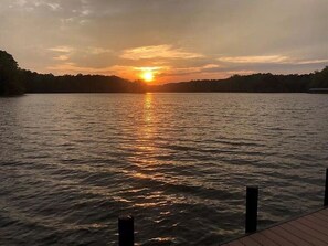 Un coucher de soleil sur un lac paisible, avec une jetée en bois au premier plan.