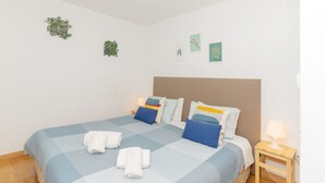 A neatly made bed with blue bedding and white towels, a bedside lamp, and wall art. - Sunny Oporto, Douro Apartments (Porto)
