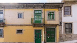 A yellow building with green doors and windows, a small balcony, and a stone facade. - Sunny Oporto, Douro Apartments (Porto)