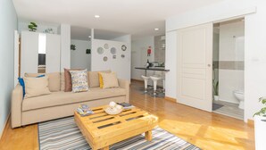 A living room with a sofa, coffee table, and a kitchen area visible through an open door. - Sunny Oporto, Douro Apartments (Porto)