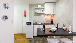 A compact kitchen with white cabinets, a microwave, a coffee maker, and a small refrigerator. - Sunny Oporto, Douro Apartments (Porto)