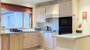 A compact kitchen with a window, a microwave, a toaster, and a fire extinguisher.