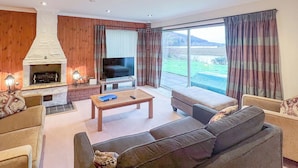 A living room with a fireplace, a television, and a large window with curtains.