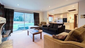 A spacious living room with a large window, a sofa, a coffee table, and a fireplace.