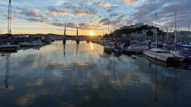 A marina with boats docked, a bridge, and buildings in the background during sunset. - Leighwood Cottage is perfect for a romantic getaway. (Paignton)