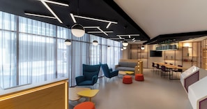 Un espacio de oficina moderno con ventanas amplias, mobiliario contemporáneo y una variedad de zonas de estar.