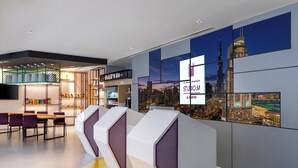 A modern hotel lobby with a reception desk, seating area, and cityscape views.