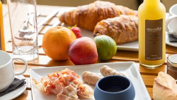 A breakfast table with croissants, fruits, bacon, and juice.