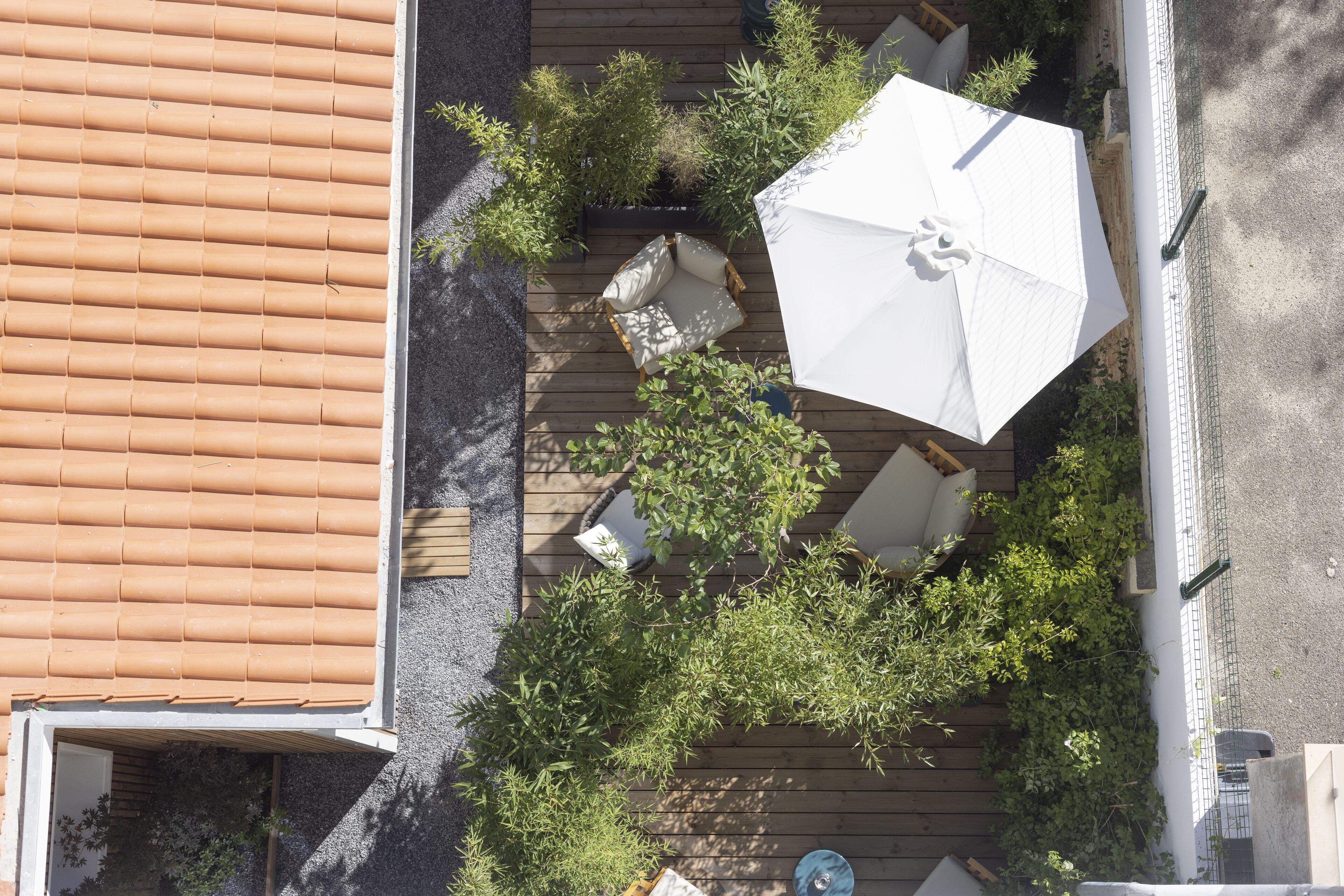 A rooftop patio with a wooden deck, white outdoor furniture, and a large umbrella.
