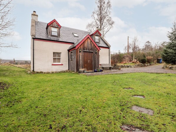 Une maison de campagne au toit en pente, avec une porte en bois et un petit porche.