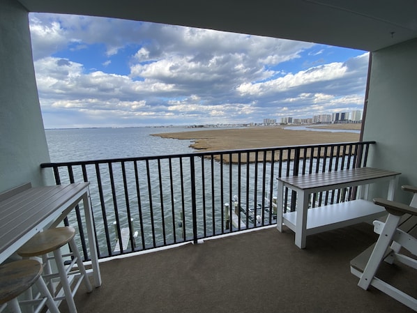 Un balcon avec vue sur la plage et l’océan, une table et deux chaises.
