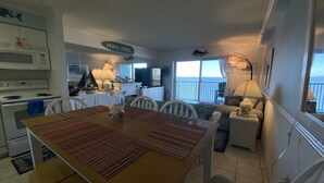 A kitchen with a dining table, chairs, a microwave, and a sign that reads "BEACH HOUSE". - ★★★★★ Sleeps 6,Linens &Towels✓ Free Parking✓ Sunset View✓ Smart TVs✓ Pool ✓ (Ocean City)