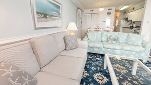 A living room with a sofa, a patterned rug, and a dining area with a table and chairs. - ★★★★★ Sleeps 6,Linens &Towels✓ Free Parking✓ Sunset View✓ Smart TVs✓ Pool ✓ (Ocean City)