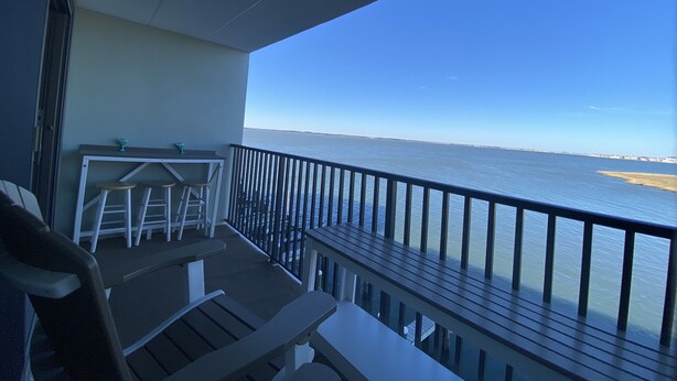 A balcony with a view of the sea, a table, and two chairs. - ★★★★★ Sleeps 6,Linens &Towels✓ Free Parking✓ Sunset View✓ Smart TVs✓ Pool ✓ (Ocean City)