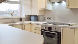 A modern kitchen with a built-in oven, a microwave, and a toaster. - Princess Court Apartment (Llanelli)
