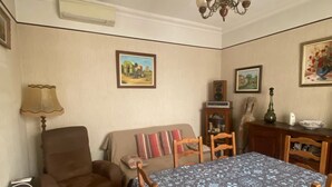 A dining area with a table set for four, a sofa, a chair, and a ceiling fan.