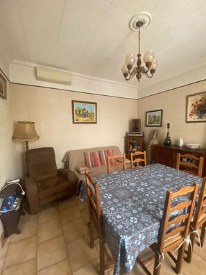 Un coin repas avec une table dressée pour quatre personnes, un canapé, une chaise et un ventilateur de plafond.
