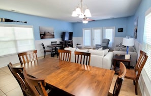 A dining area with a wooden table and chairs, a television, and a sofa.