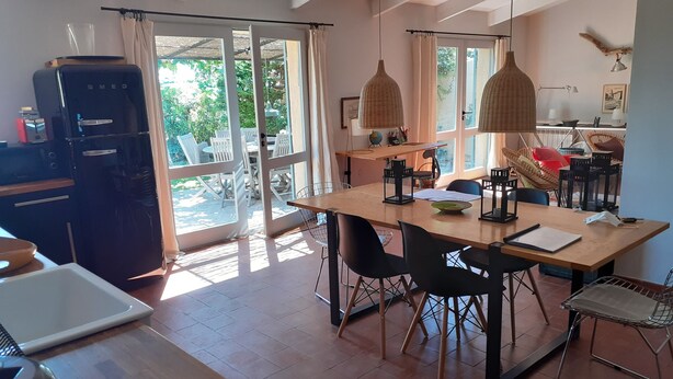 A spacious dining area with a large table, chairs, and a kitchen area visible through an open door. - mas (La Londe les Maures)