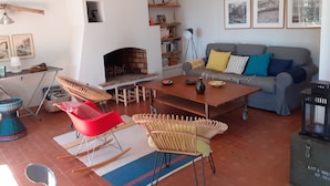 A living room with a fireplace, a sofa, a coffee table, and wicker chairs. - mas (La Londe les Maures)