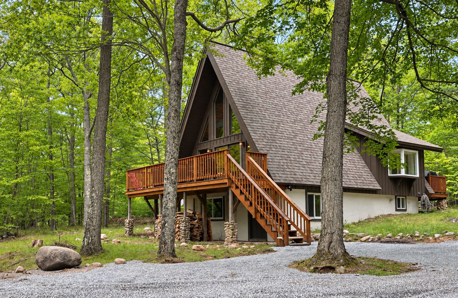 Une cabane dotée d’une terrasse en bois, d’un escalier et de fondations en pierre.