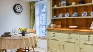 A dining area with a round table, chairs, a clock, and a window with curtains. - The Hayloft - UK37563 (Crosby Garrett, near Kirkby Stephen)
