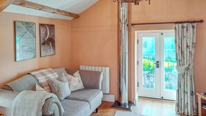 A cozy living room with a sofa, a radiator, a window with curtains, and artwork on the wall. - The Hayloft - UK37563 (Crosby Garrett, near Kirkby Stephen)
