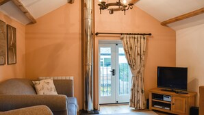 A cozy living room with a sofa, TV, and a fireplace. - The Hayloft - UK37563 (Crosby Garrett, near Kirkby Stephen)
