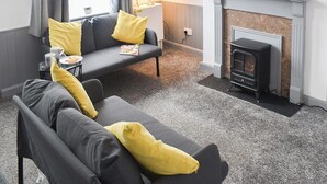 Una sala de estar con sofá, chimenea y lámpara.