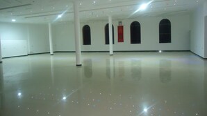Un interior espacioso y luminoso, con piso pulido, paredes blancas y una serie de ventanas de arco.