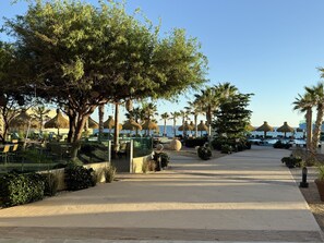 Een resort met buitenmeubilair, palmbomen en uitzicht op zee.