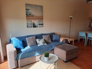 Ein modernes Wohnzimmer mit Sofa, Couchtisch mit Pflanze und Essbereich mit Stühlen und Tisch.