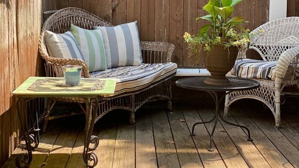 A wooden deck with wicker furniture, including two chairs and a small table with a candle. - Cozy English Basement Apt quiet but close to downtown (Winchester)