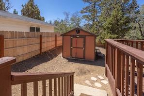 Un espace extérieur clos, doté d’une terrasse en bois, d’un petit abri de jardin et d’un bâtiment avec une fenêtre.