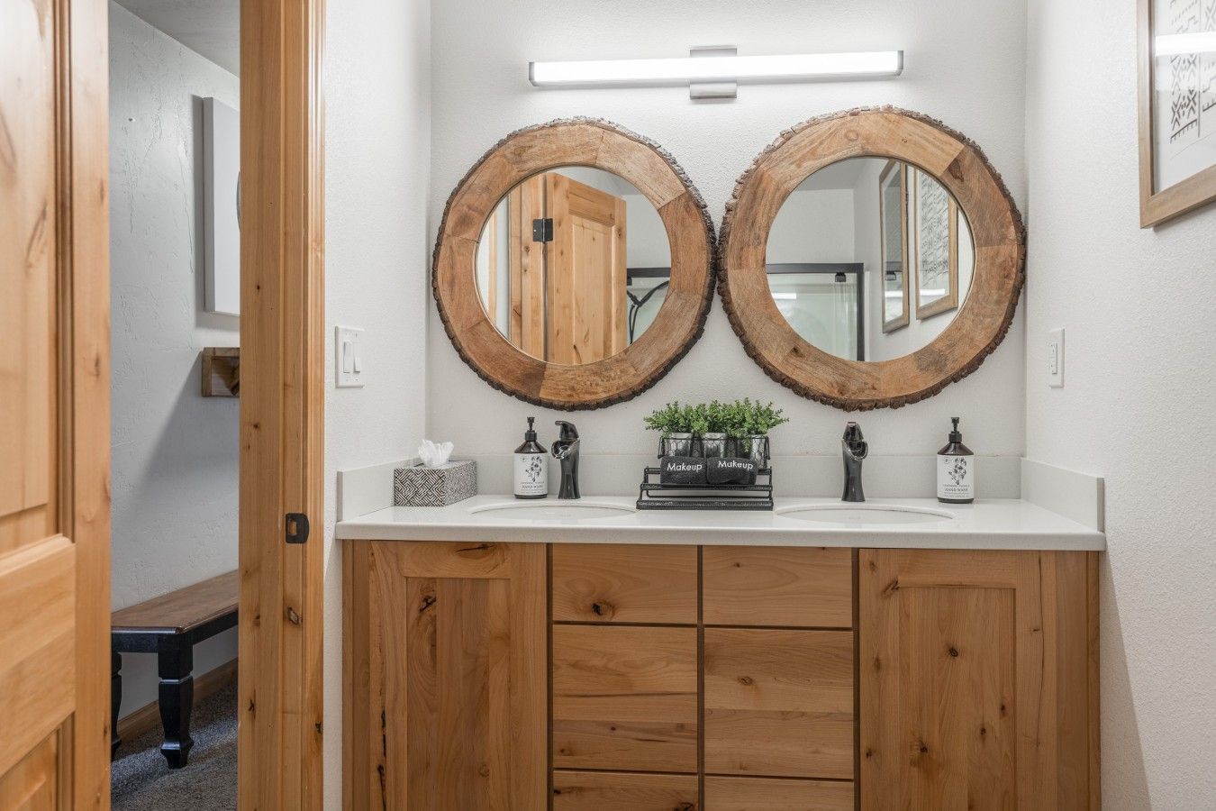 Ein Badezimmer mit zwei spiegelnden Holzbögen, einer weißen Ablage und einem Holzkonsolentisch mit Schubladen.